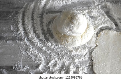 Gray texture background. A lump of dough with scattered flour on the table.