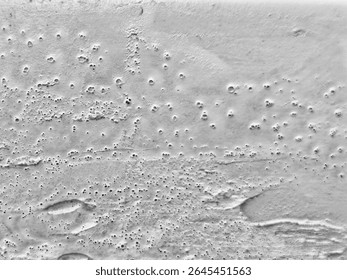 Gray textured surface with numerous small craters and variations.