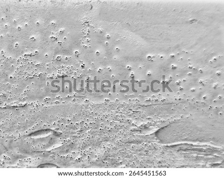 Gray textured surface with numerous small craters and variations.