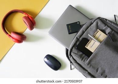 Gray urban backpack with a laptop, notepad, fountain pen, external ssd, mouse, headphones and smartphone. The concept of a backpack and gadgets for study. Modern student's bag. Close-up - Shutterstock ID 2170503937