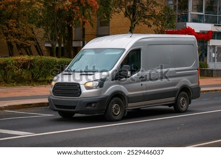 A gray van at an intersection downtown. Delivery truck. A gray van at an intersection downtown. Delivery truck in the fall on a city street with stores
