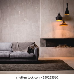 Gray velour sofa in a dark room the bright light from eternal light, and artificial fireplace. Interior loft with concrete walls - Shutterstock ID 559253560
