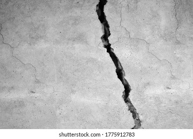 The gray wall of the house with a huge crack. Black and white.
