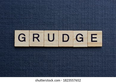 Gray Word Grudge From Small Wooden Letters On A Black Table