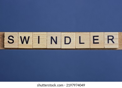 Gray Word Swindler From Small Wooden Letters On A Black Table