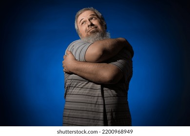 A Gray-haired, Bearded, Disheveled Adult Man In A Striped Shirt Tries To Scratch His Back With His Hand, But He Is Too Big For This Operation And Has A Displeased Expression On His Face. Scabies Conce