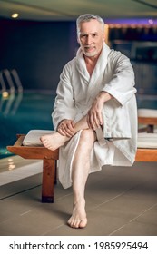 A Gray-haired Bearded Man In A White Bath Robe In Spa Center