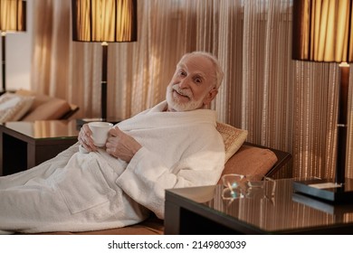 A Gray-haired Bearded Man In A White Robe In A Hotel Room