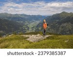 Gray-haired man with backpack standing on mountain and looking at further route up, Austria
