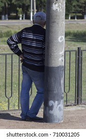 a gray-haired man is waiting in the shadow behind the pillar