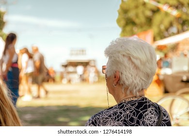 Gray-haired Older Woman Seen From Behind At A Fair