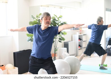 Gray-haired senior man doing yoga indoors