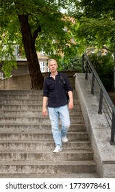 gray-haired young man with a backpack goes down the stairs in the park. High quality photo