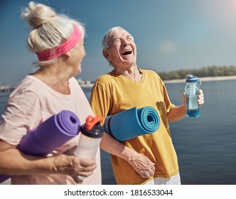 Gray-headed elderly man with closed eyes laughing heartily in front of a smiling Caucasian woman - Powered by Shutterstock