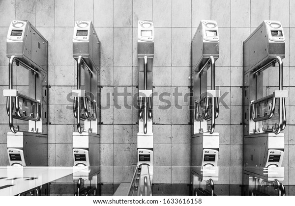 A grayscale aerial shot of automatic card\
scanners in a train station