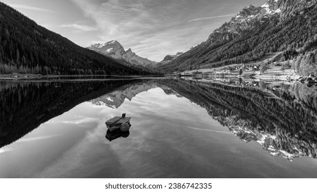 A grayscale  of a boat in a body of water surrounded by mountain range in Switzerland - Powered by Shutterstock