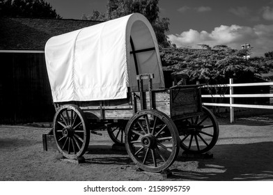 A Grayscale Of A Cowboy Wagon In A Field