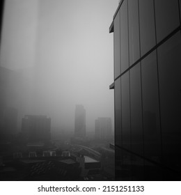 A Grayscale Of A Modern Tall Building Wall On A Foggy Day