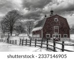 A grayscale shot of a barn in the snowy countryside under a gloomy sky