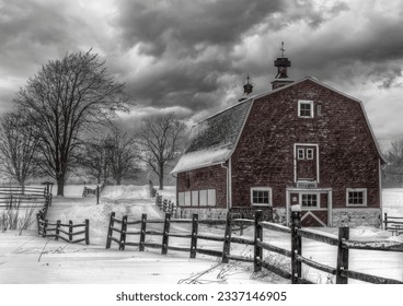 A grayscale shot of a barn in the snowy countryside under a gloomy sky