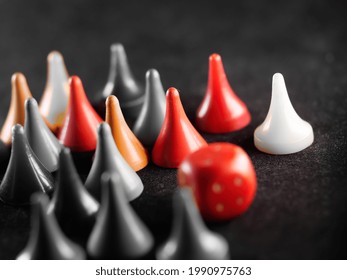 A grayscale shot of board game pieces next to dice on the floor with some of them colored