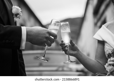 A Grayscale Shot Of Bride And Groom Making A Toast With Champagne