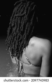 A Grayscale Shot Of A Rasta Woman With Curly Hair In A Swimsuit In The Water