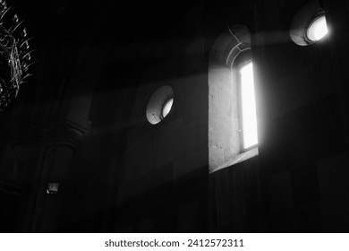 A grayscale of sunlight streams through a window in a church