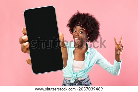 Great App. Cheerful Excited Black Woman Holding Smartphone With Blank Screen And Gesturing Peace, Funny African American Female Recommending New Mobile Application Or Website, Mockup Image