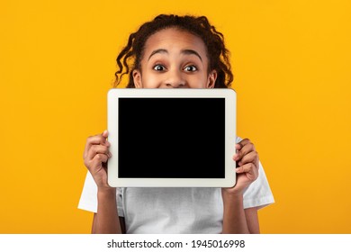 Great Application. Excited Black Girl Holding And Showing Digital Tablet With Empty Screen For Mockup, Covering Face And Mouth, Recommending New App Posing Standing Over Yellow Studio Background - Powered by Shutterstock