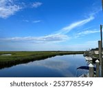 Great Bay, NJ - tranquil NJ coast bay with calm reflections, grassy marshes, and a docked marina under a bright blue sky with soft clouds.