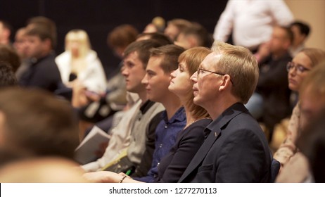 Great Britain - London, 10 December 2018: Close Up For Interested Audience At A Business Seminar Listening To A Speaker. Stock. Side View Of Rows With People In Conference Hall Listening To Presenter.