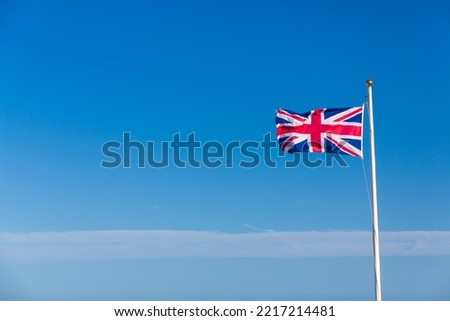Great British flag the Union Jack flying in a breeze against a blue sky with a line of wispy clouds with space for copy
