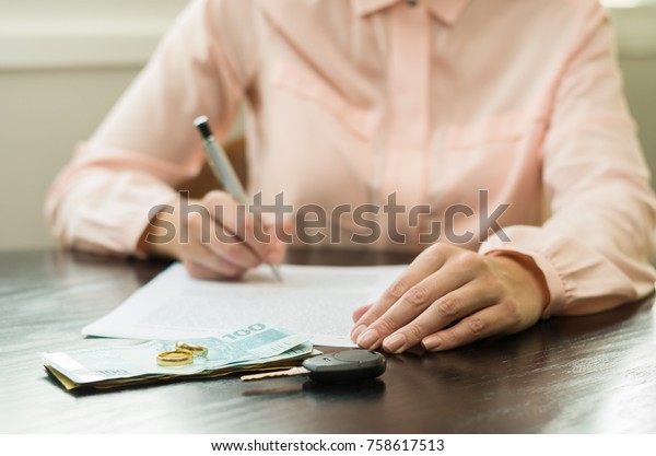 Great\
concept of divorce, end of relationship, young woman signing\
divorce agreement. Money, car key on the\
table.