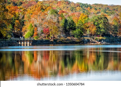 Great Falls trees reflection during autumn in Maryland colorful yellow orange leaves foliage by famous Billy Goat Trail people walking hiking on bridge