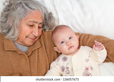 Great Grandma and great granddaughter snuggling on white sheet