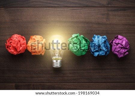 great idea concept with crumpled colorful paper and light bulb on wooden table