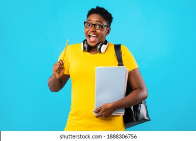 Great Idea. Excited Black Female Student Pointing Pencil Up Having Inspiration Moment Posing With Books Over Blue Studio Background. Eureka Concept. College And University Scholarship And Study