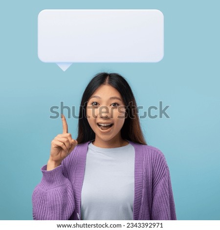 Great idea, inspiration concept. Portrait of positive asian lady raising finger up, showing blank speech balloon and smiling, having wow creative idea, standing over blue studio background