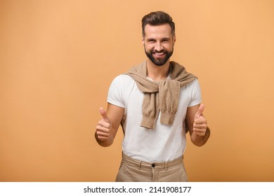 Great job. Portrait of smiling satisfied male person standing with thumbs up, like gesture, demonstrating approval and agree with suggestion. Indoor studio shot isolated