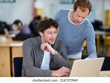 Great Minds Think Alike. Shot Of Two Coworkers Working Together On A Laptop In A Casual Work Environment.