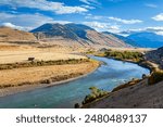 Great Missouri River. USA. The Missouri River is tributary of the Mississippi River. The clouds are reflected in the water. The bed of the deep river bends into the hilly banks. 