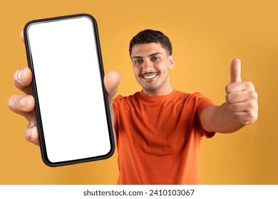 Great offer. Cheerful brazilian man in casual holding huge phone with white blank screen and showing thumb up, recommending online shopping and easy fast banking, orange studio background - Powered by Shutterstock