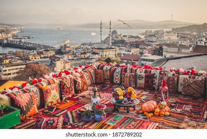 Great panoramic view of Istanbul from high terrace decorated traditional colorful ornamental pillows and carpets and stillife with fruits, turkish tea and hookkah