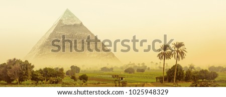 Great pyramid of Khafre in Egypt. Fantasy of egyptian landscape with ancient pyramid of Chephren in morning haze. Wide panorama in green oasis with fields and palm trees for your banner or header.