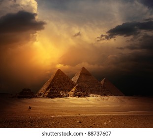 Great pyramids in Giza valley with yellow dark clouds on the background