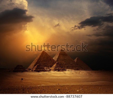 Great pyramids in Giza valley with yellow dark clouds on the background