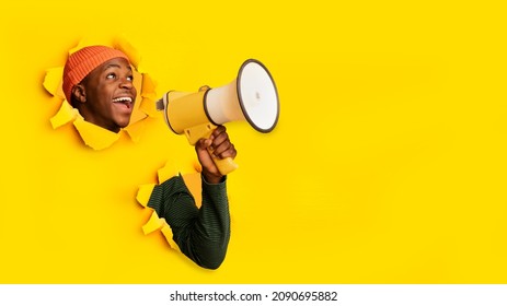 Great sale. Emotional young black guy shouting into megaphone through hole in ripped orange paper, banner design with free space. African American man making announcement, having special offer - Powered by Shutterstock