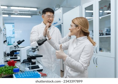 Great teamwork of scientists, an Asian man and a woman working in the laboratory, are happy about the success and the result of the research. Congratulate each other and show the super finger. - Powered by Shutterstock