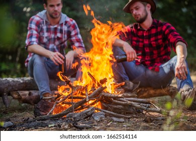 great time together. two men relax at fire. hiking and camping. male friendship. drink beer bonfire. ranger at outdoor activities. spend picnic weekend in nature. Adventure concept. hike and people.